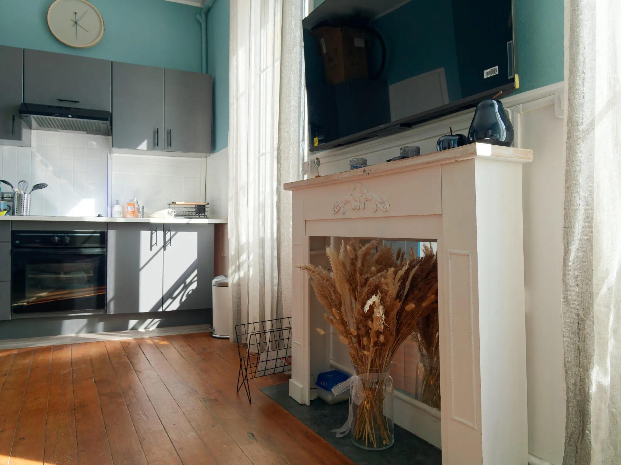 Studio sitting corner with white fireplace, pampas bouquet and sun on the wooden floor