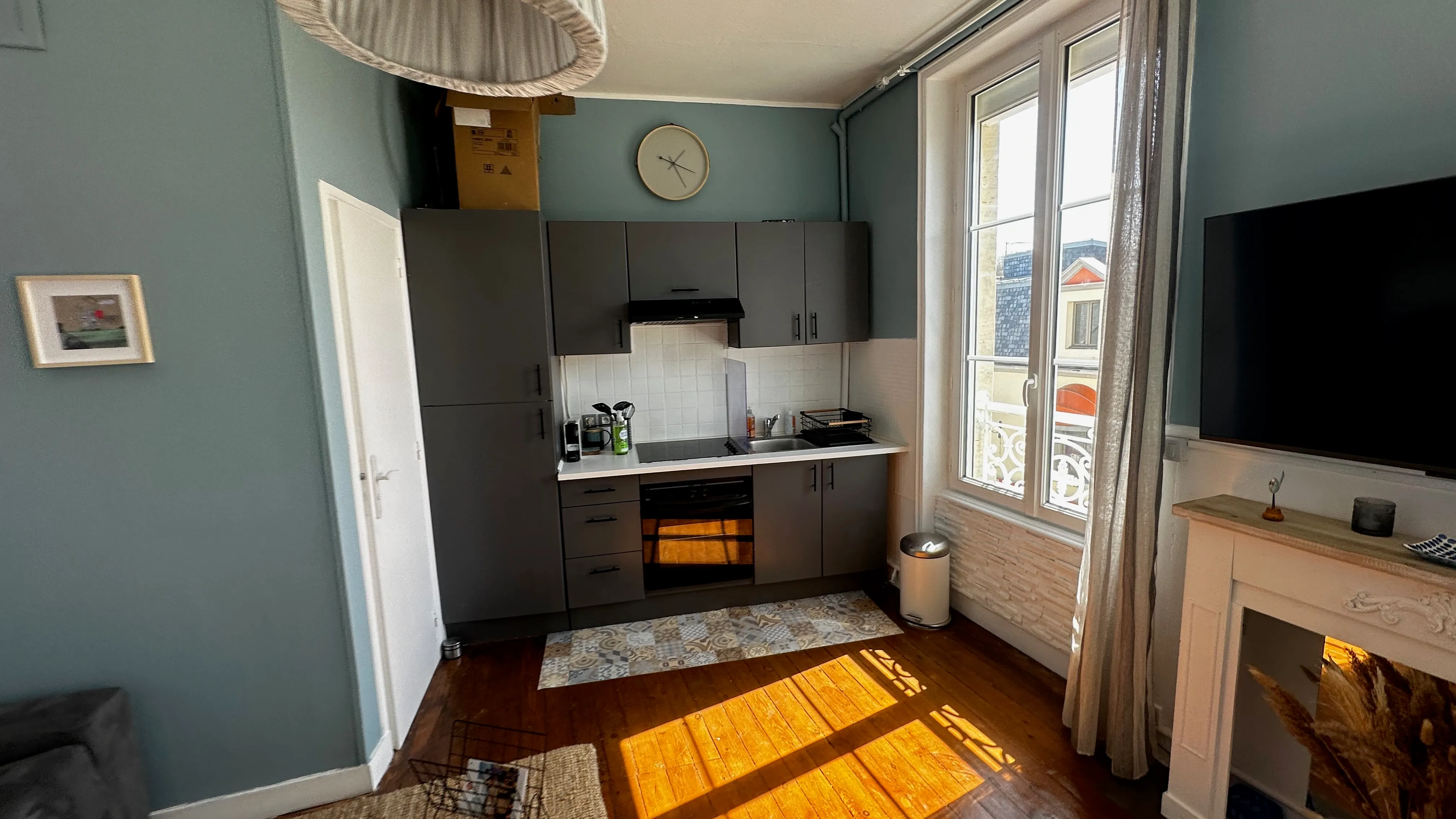 Studio kitchen in the morning light, window open onto the village rooftops
