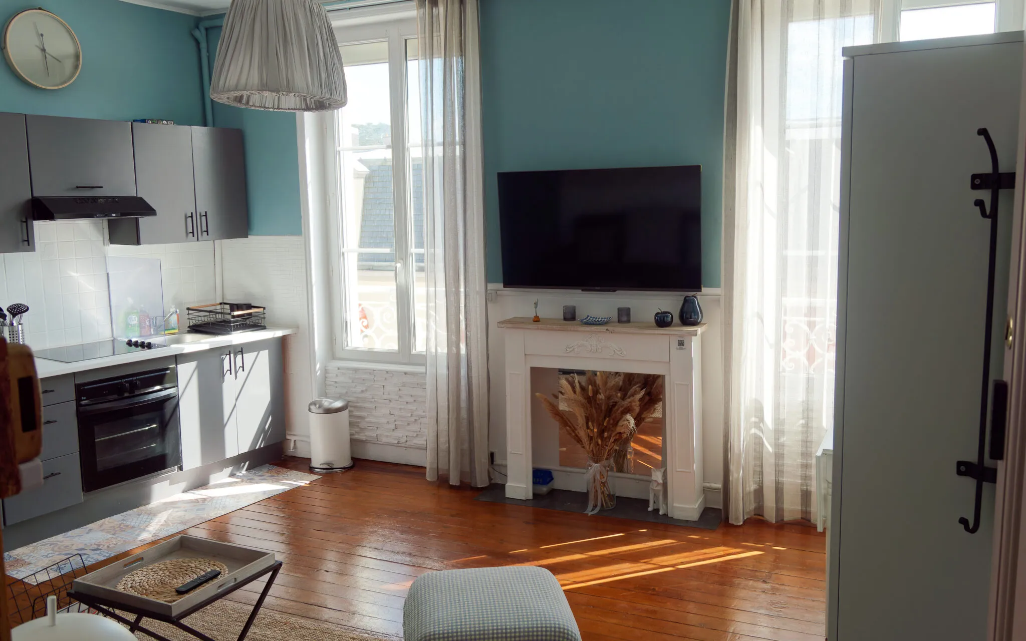 Studio living room with teal walls, old wooden floor and decorative fireplace